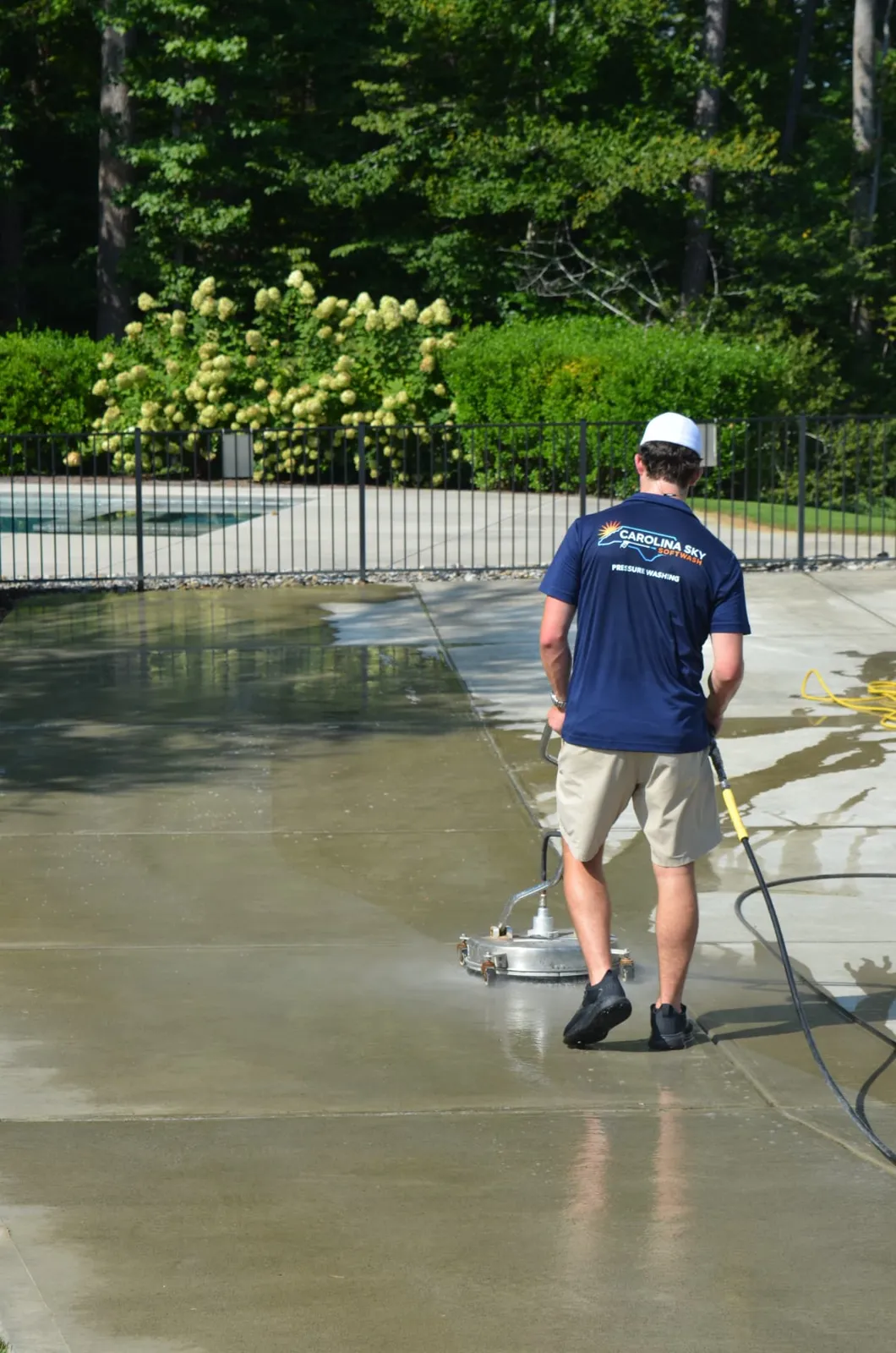 Technician surface cleaning a wet concrete pool deck