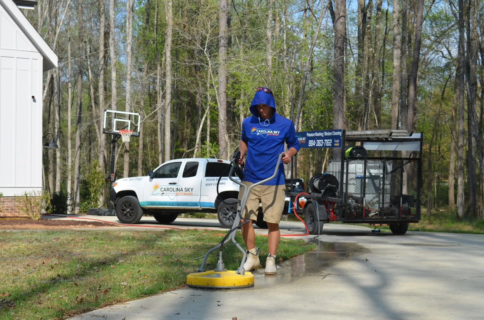 Driveway cleaning with a rotary surface cleaner beside the Carolina Sky Softwash truck