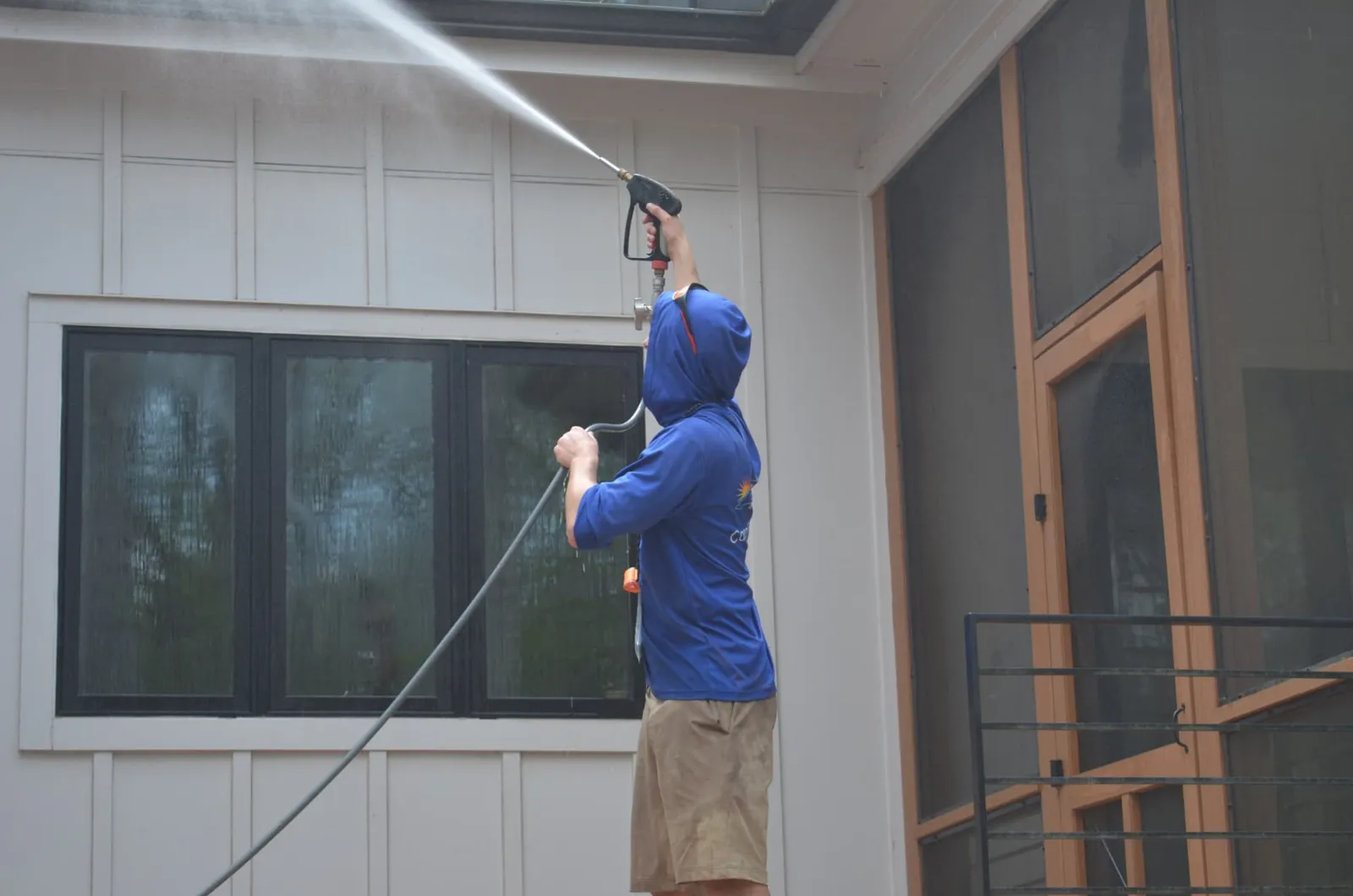 Soft washing soffits and siding above black-framed windows on a Triangle-area home