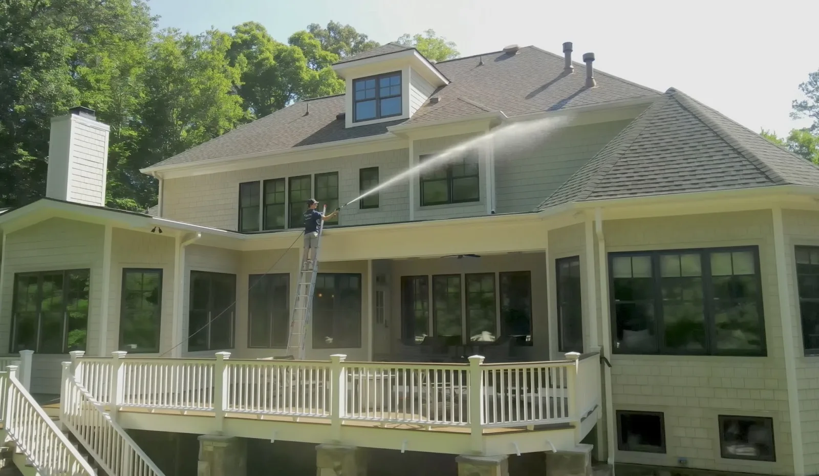 Soft washing the roofline and upper story of a large two-story home