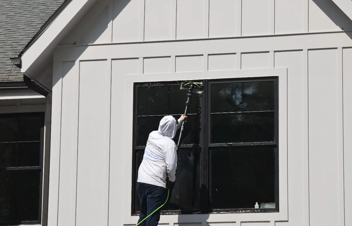 Cleaning black-framed windows with a water-fed pole