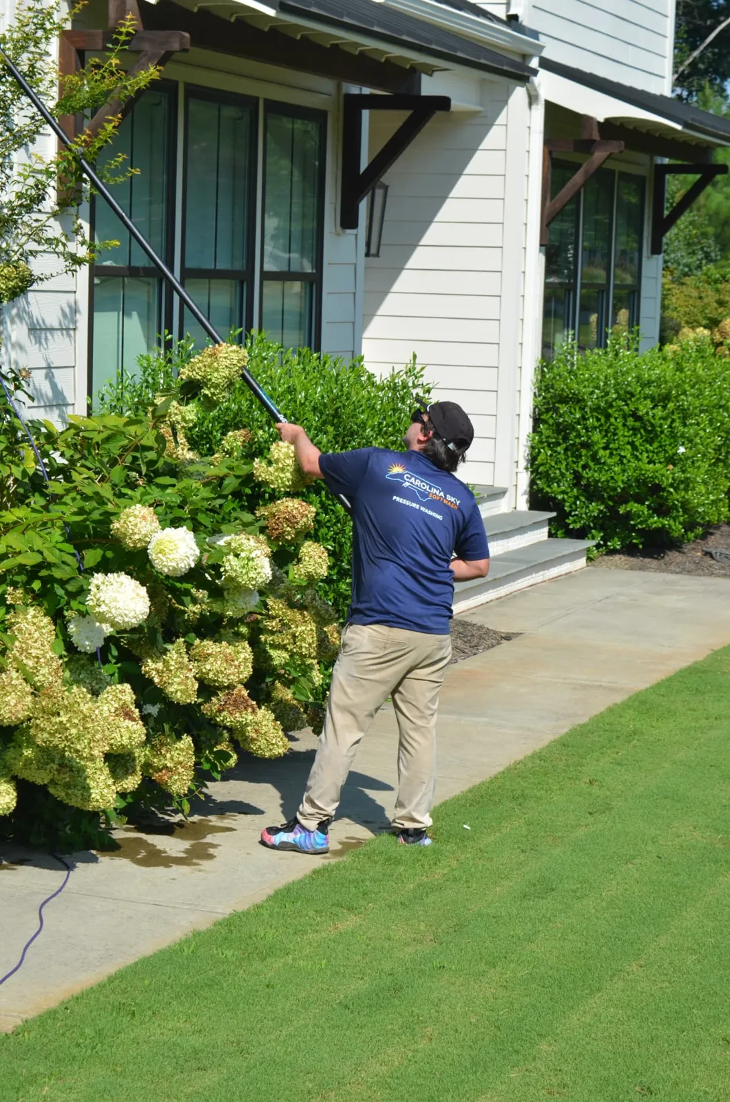Technician cleaning front porch windows with a water-fed pole