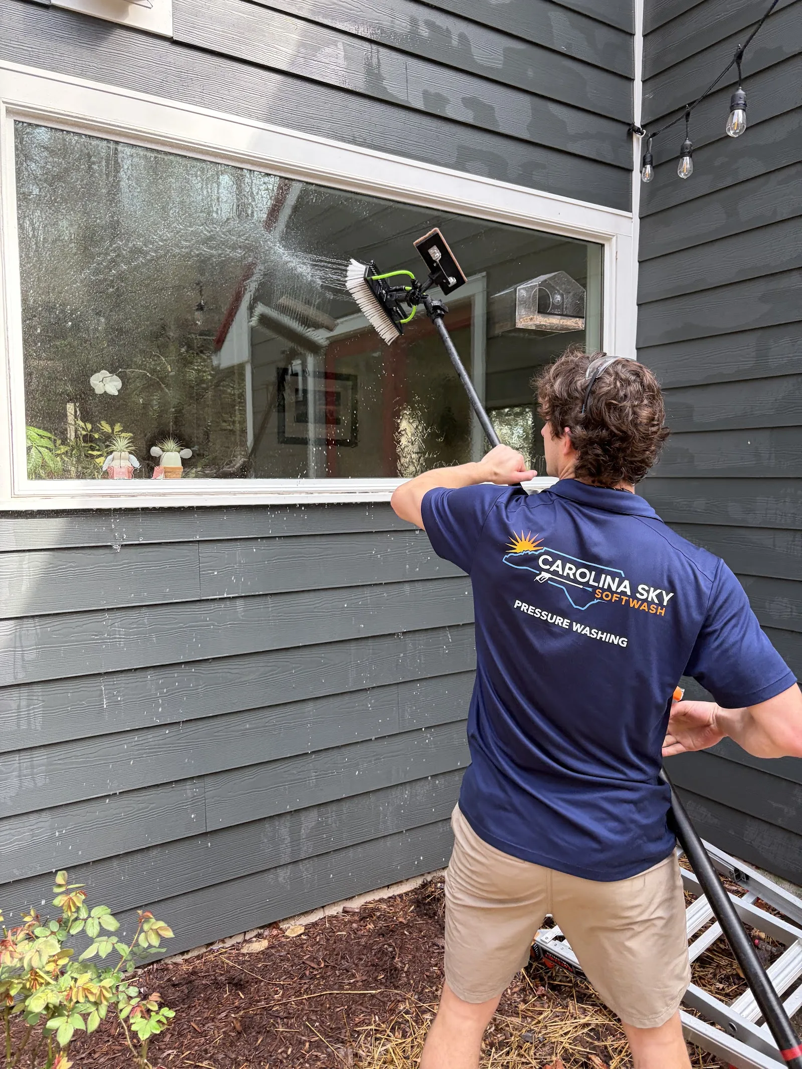 Technician scrubbing an upper window with a water-fed pole